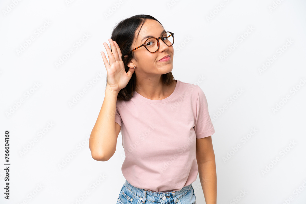 Young caucasian woman isolated on white background listening to something by putting hand on the ear