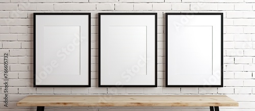 Three empty picture frames are placed on a rustic wooden bench situated against a textured brick wall photo