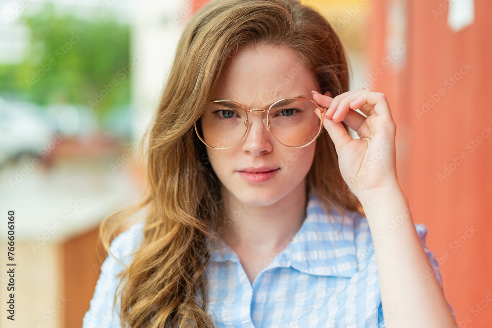 Young redhead woman at outdoors With glasses and frustrated expression Young redhead woman at outdoors With glasses and frustrated expression