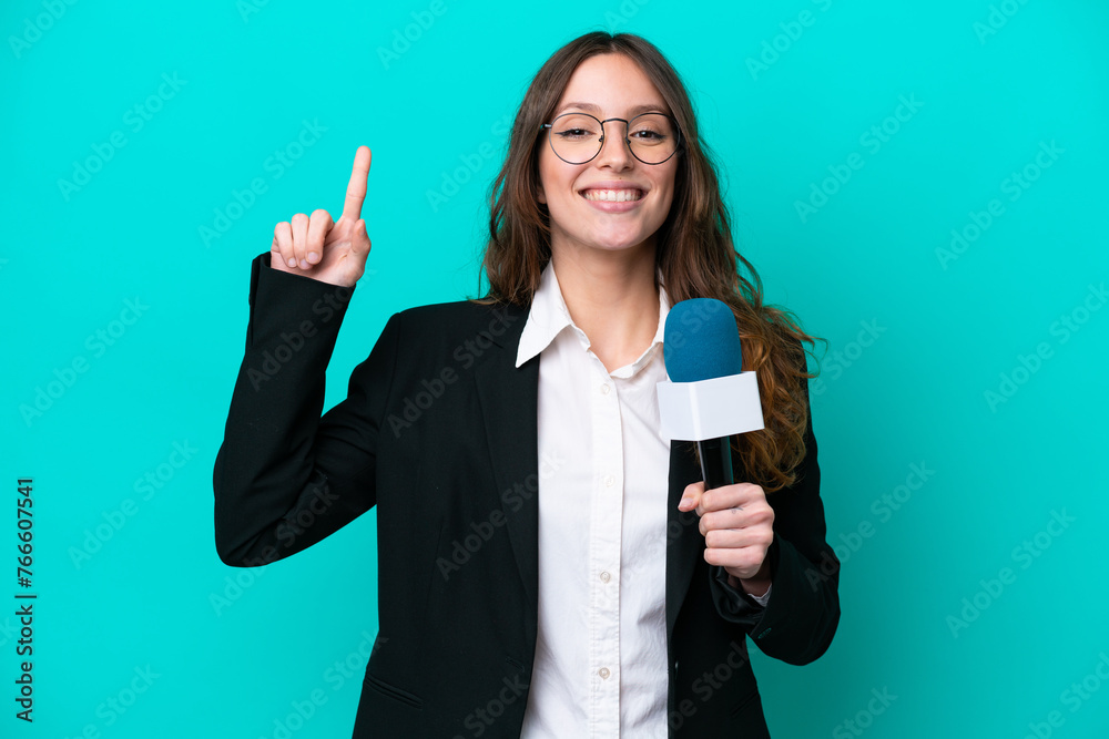 Obraz premium Young TV presenter woman isolated on blue background pointing up a great idea