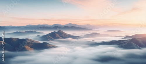 View of fog and clouds engulfing the mountains during sunset, with a dramatic sky in the background