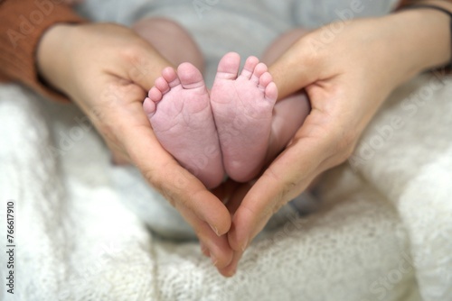 Mother hands holding newborn feet in heart shape
