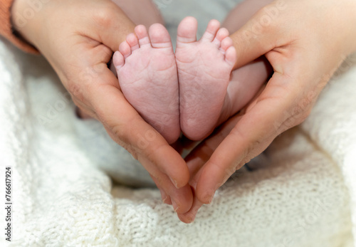 Mother hands holding newborn feet in heart shape