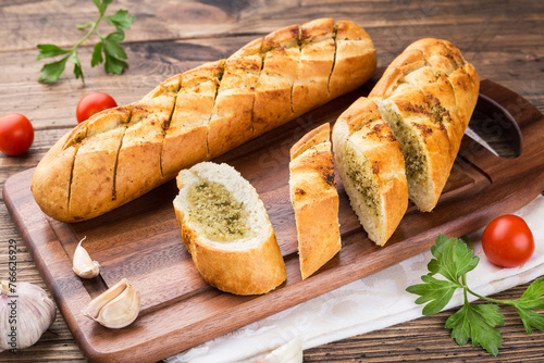garlic baguette roll on a wooden cutting board © Elena Elizarova