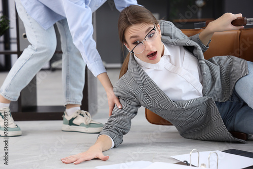 Photography Young businesswoman fell down from chair getting help in office