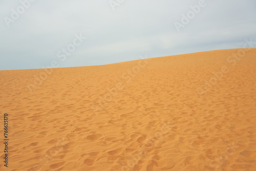 Sand dune in the desert with clouds in the background.