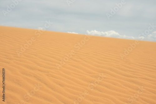 Sand dune in the desert with clouds in the background.