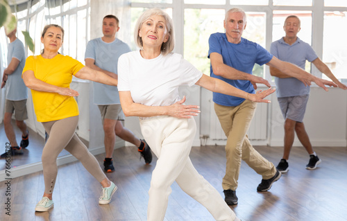 Group of aged people rehearsing sports dance in dance hall