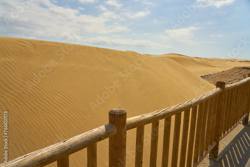 Sand dunes behind a wooden fence.