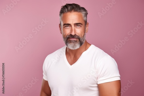 Portrait of handsome mature man in white t-shirt on pink background.