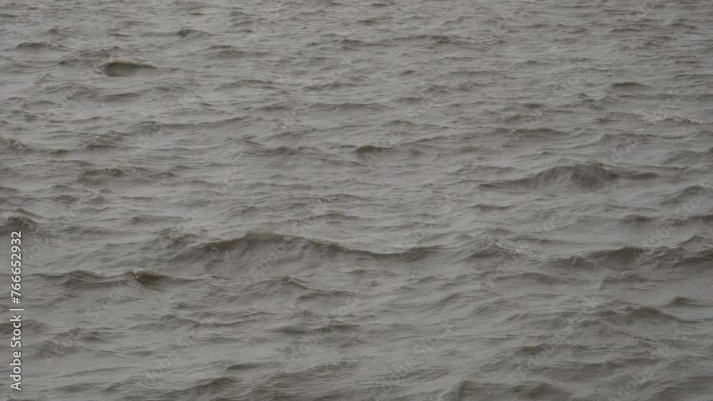 Slow motion of river flowing close up on windy day