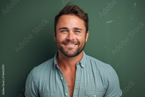 Portrait of a handsome man smiling at the camera against a green chalkboard