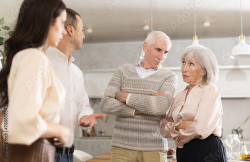 Young man introducing his future wife to his mom and dad demonstrating disagreeable attitude during meeting at home