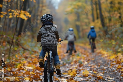Kids cycling on a forest path in the autumn woods
