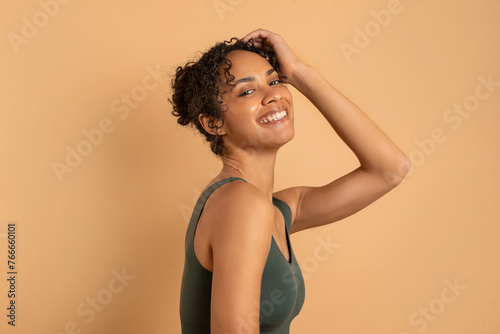 Natural beauty. Portrait of latin lady standing against beige background, smiles toothy and looking at camera