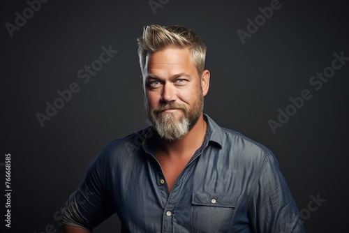 Portrait of a handsome mature man with beard over dark background. © Asier