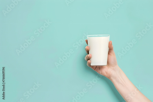 Hand holding milk glass on pastel background with ample copy space for text placement 