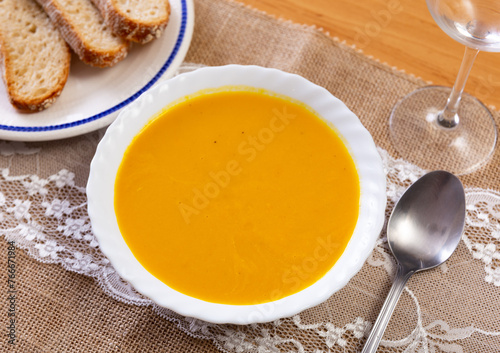 Service plate containing carrot cream with pieces of toast on the laid table in restaurant