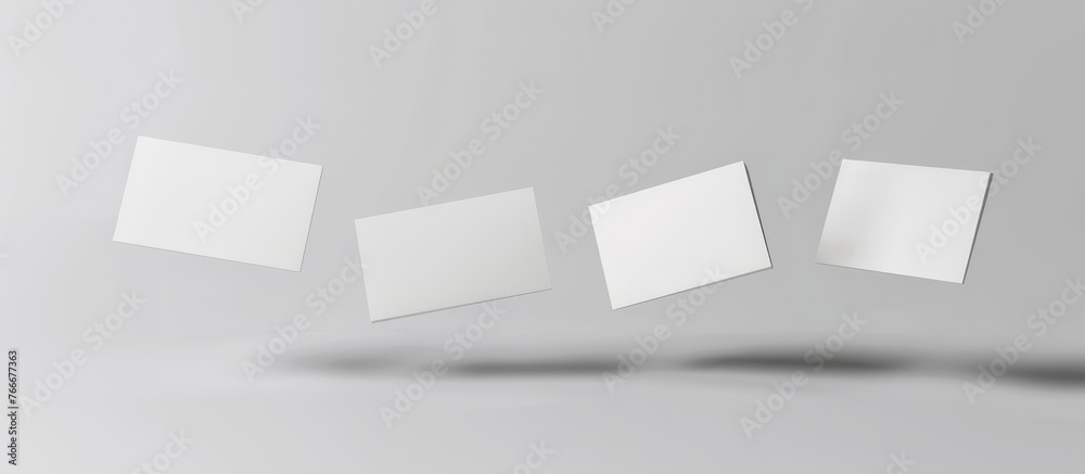 Front view of four surreal white business cards floating in mid-air on a white background for a mockup; an actual photo, not a 3D rendering. Front view of four surreal white business cards floating in mid-air on a white background for a mockup; an actual photo, not a 3D rendering.