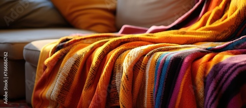 Cozy setting with a close up of a soft blanket strewn over a comfortable couch, accompanied by fluffy pillows