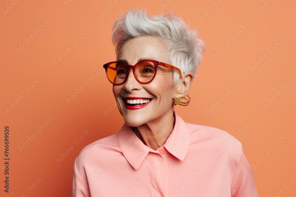 Cheerful senior woman in eyeglasses on orange background.