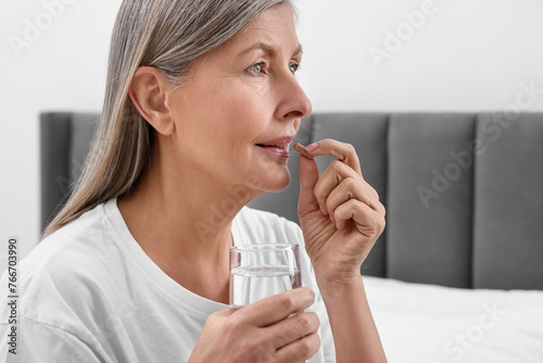 Beautiful woman taking vitamin pill in bedroom