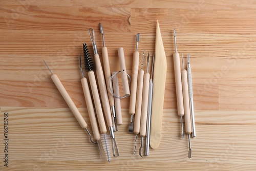 Set of different clay crafting tools on wooden table in workshop, flat lay