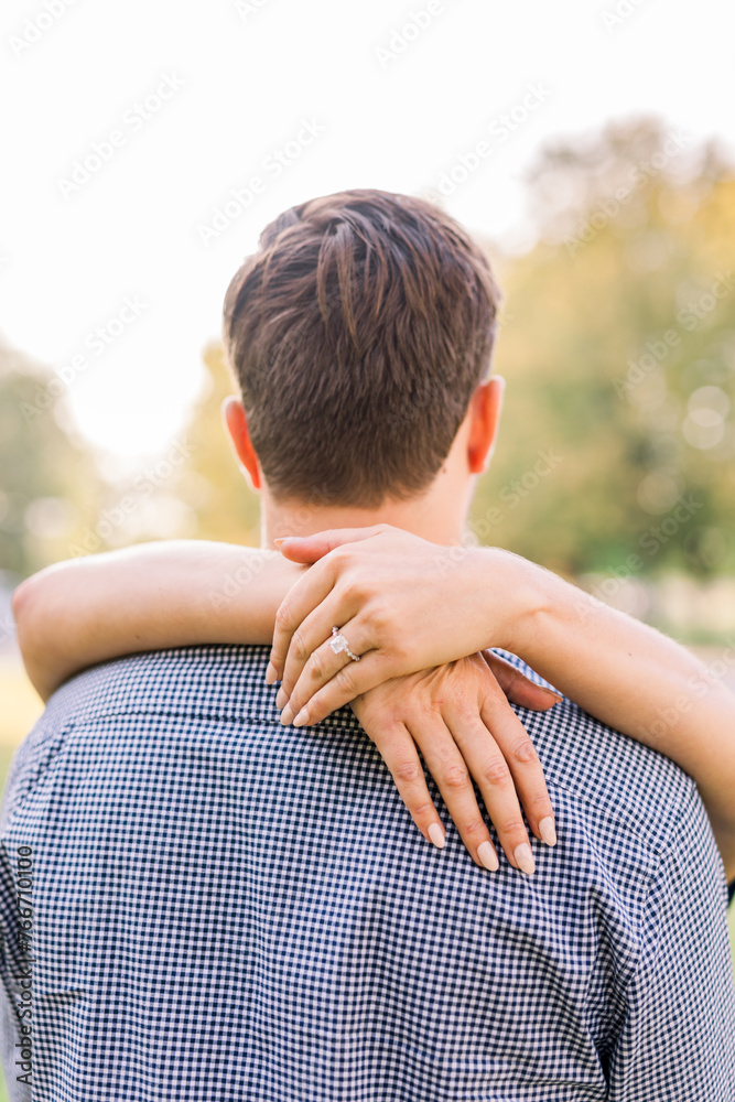 An engaged woman has her arm looped around her fiance's neck showing off her engagement ring. An engaged woman has her arm looped around her fiance's neck showing off her engagement ring.