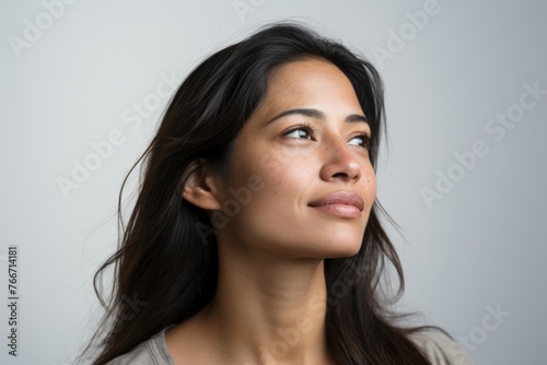 Close up portrait of a beautiful young woman looking up over gray background