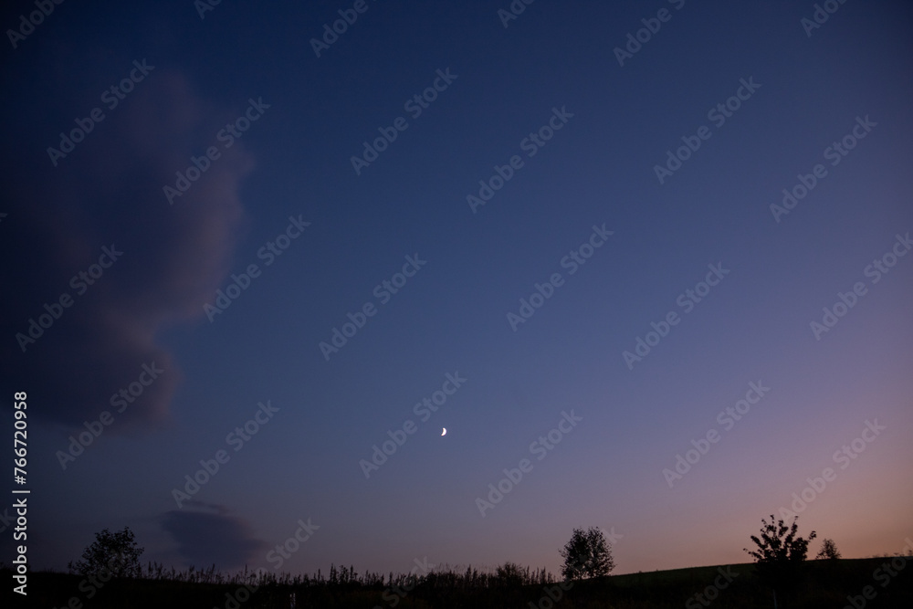Naklejka premium 秋の晴れた夕暮れの空の三日月と丘 