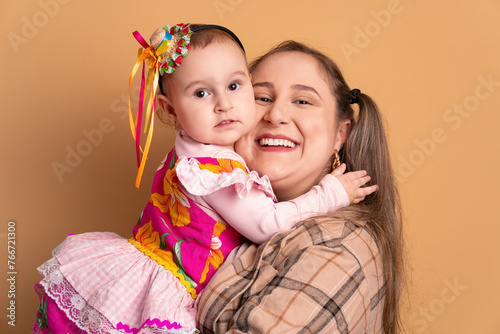 happy mother and daughter to Brazilian Junina Festival in beige studio background. hugging each other 