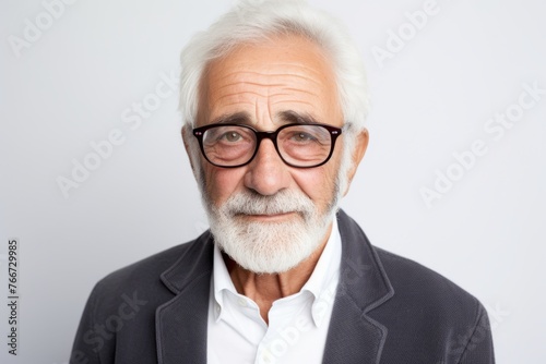Portrait of a senior man with eyeglasses against grey background © Inigo
