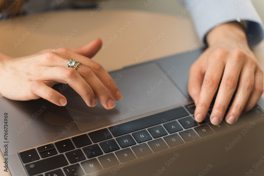 Hands of an executive woman dressed formally in a light blue shirt typing on her laptop Hands of an executive woman dressed formally in a light blue shirt typing on her laptop