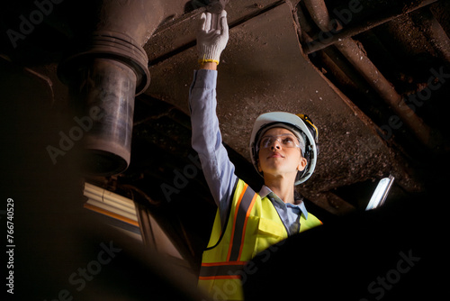 Portrait of railway technician worker in safety vest and helmet working with blueprint at train repair station photo