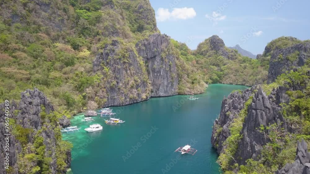 Aerial Forward Descending Shot Of Outriggers Moving On Rippled Sea Between Rock Formations During Sunny Day - Palawan, Philippines Aerial Forward Descending Shot Of Outriggers Moving On Rippled Sea Between Rock Formations During Sunny Day - Palawan, Philippines