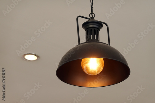 Vintage lamp hanging from the ceiling with white wall decorated in hotel