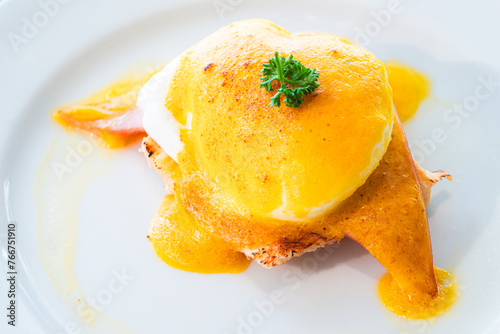 Eggs Benedict- toasted English muffins, ham, poached eggs, and delicious buttery hollandaise sauce : close up.