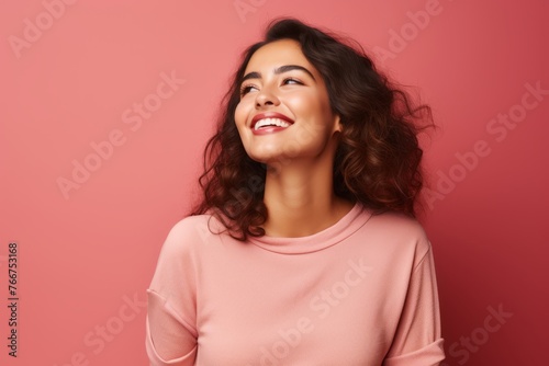 Portrait of a happy smiling young woman looking up over pink background