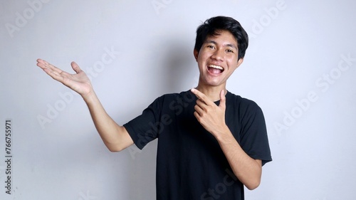 young asian man smiling gesturing with his left hand pointing to his right palm photo