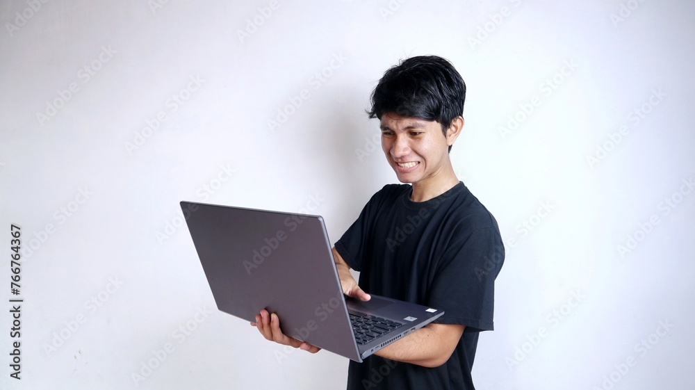 young asian man angry with gesture holding laptop with isolated white background young asian man angry with gesture holding laptop with isolated white background