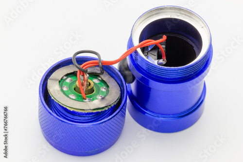 The insides of a broken blue flashlight against a white background. The image shows the parts inside everyday technology. It’s perfect for troubleshooting, repair, and electronics engineering themes. (ID: 766766766)