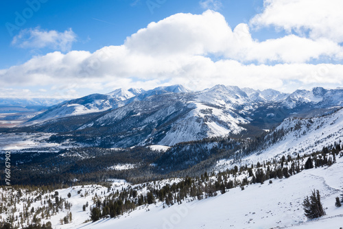 A view of snowy mountains and puffy clouds on a sunny winter day in Mammoth Lakes, CA