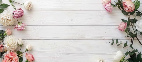 Flowers arranged on a white wooden background, captured from a top-down perspective with empty space for text.