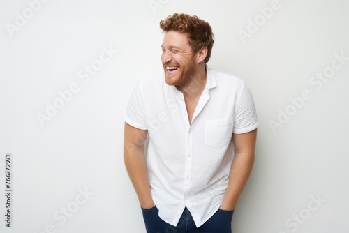 Portrait of a handsome young man laughing while standing against white background