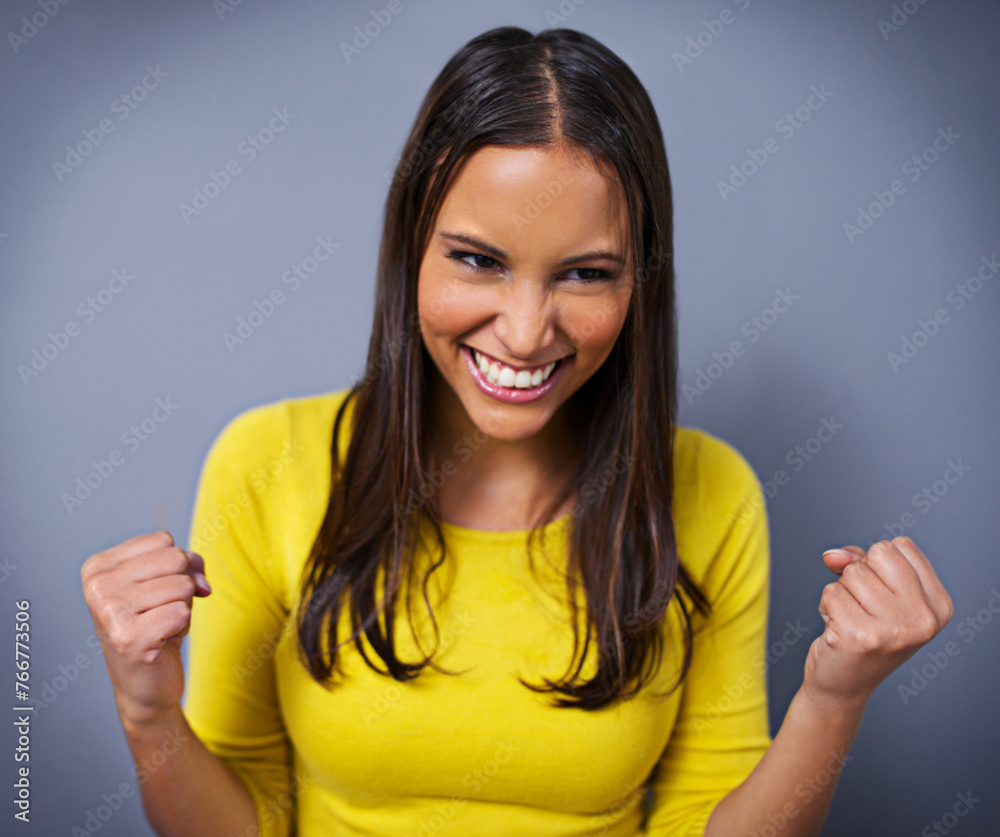 Woman, fist and celebration with smile in studio for success, goals and vision for achievement by blue background. Girl, person and winner with cheers, thinking and excited with competition in Mexico Woman, fist and celebration with smile in studio for success, goals and vision for achievement by blue background. Girl, person and winner with cheers, thinking and excited with competition in Mexico