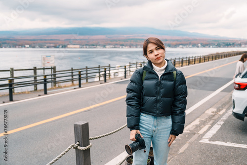 Woman tourist with Mt Fuji  at Lake Yamanaka, happy Traveler sightseeing Mount Fuji in Yamanakako village, Yamanashi, Japan. Landmark for tourists attraction. Japan Travel, Destination and Vacation photo