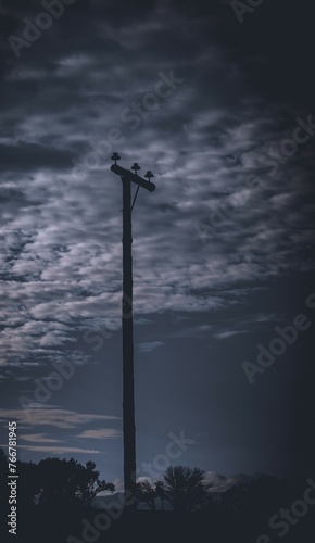 A telephone pole without telephone lines isolated in vertical format against a dark and eerie skyline image for background use