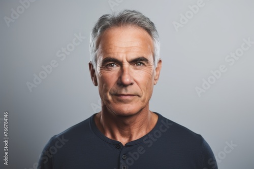 Portrait of mature man looking at camera. Isolated on grey background. © Inigo