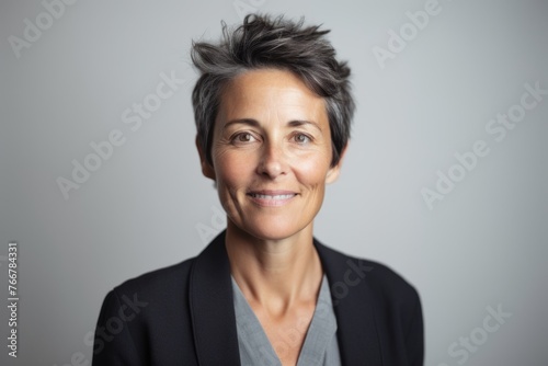 Portrait of a smiling middle aged businesswoman over grey background.