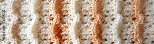 Soft focus on the textured stripes of a white and beige knitted fabric, emphasizing the cozy material.
